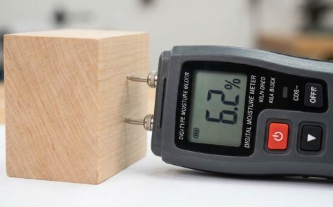 Contractor using pin-type wood moisture meter on hardwood flooring subfloor