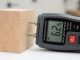 Contractor using pin-type wood moisture meter on hardwood flooring subfloor
