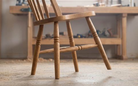 Hands applying wood glue to a loose chair leg joint during repair