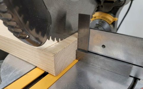 Woodworker checking miter saw blade alignment with a machinist square for a perfect 90-degree cut