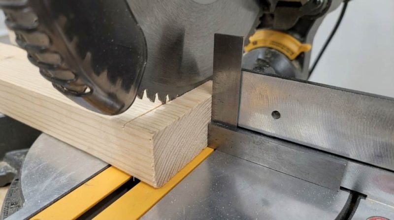Woodworker checking miter saw blade alignment with a machinist square for a perfect 90-degree cut